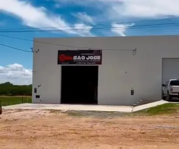 Vista da oficina a partir da estrada, com o letreiro na fachada